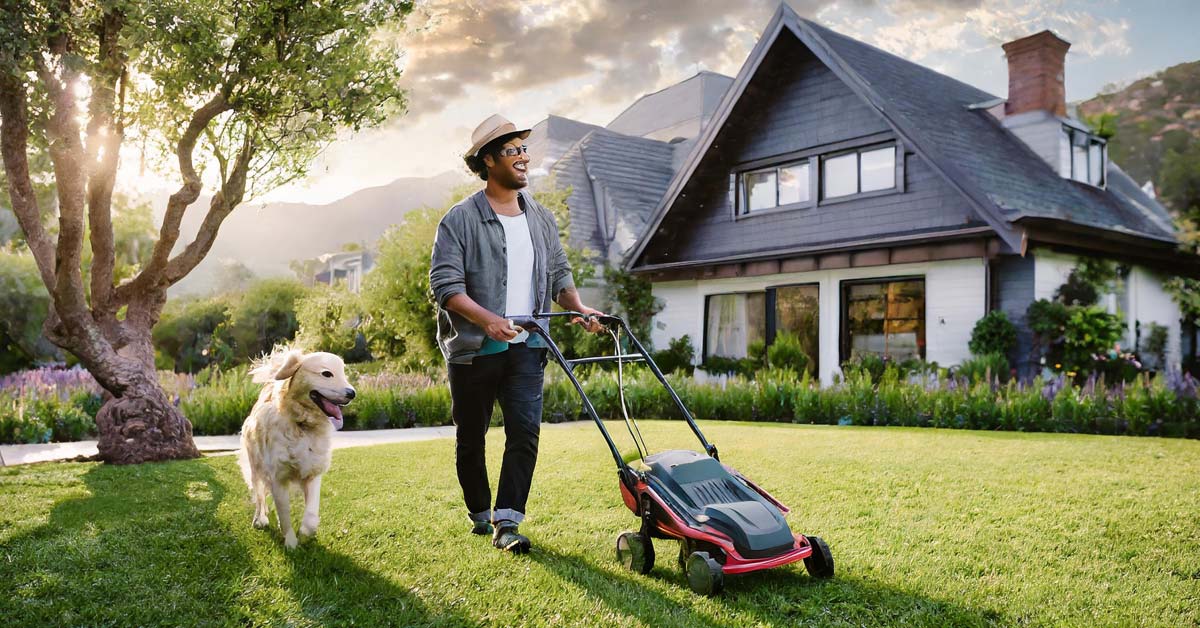 Image of a cheerful man mowing his lawn with a dog by his side in front of a picturesque house, symbolizing the enduring value and personal connection of business blogging.